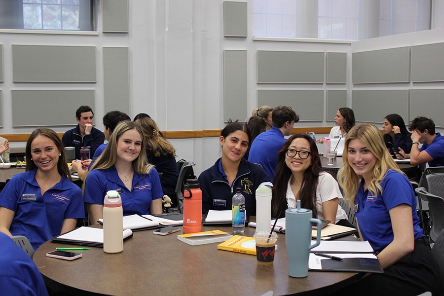 Students smiling around a table. 