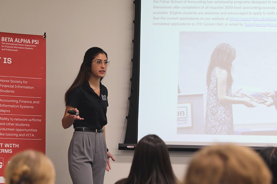 Student presenting to other students sitting in front of her.