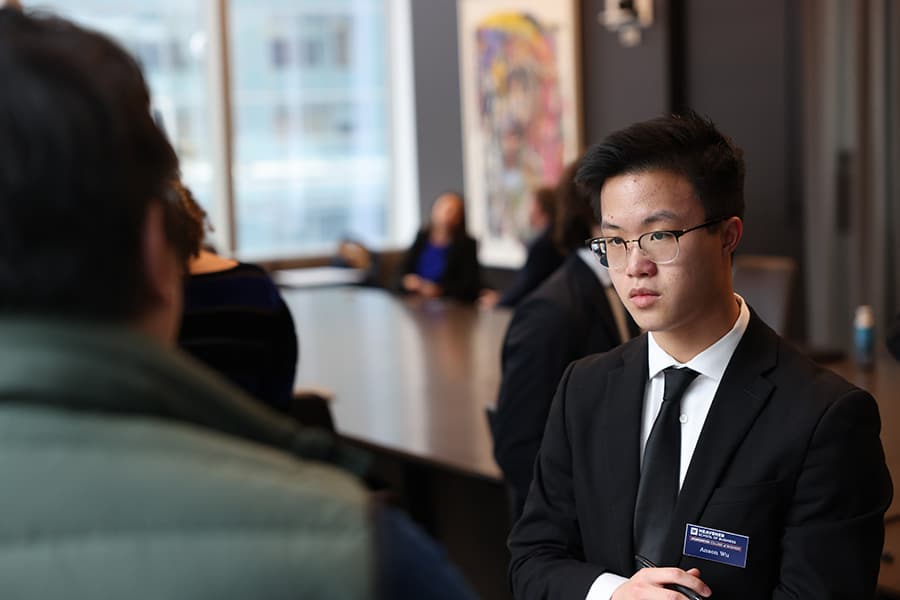 Student in professional attire talking to an employer.