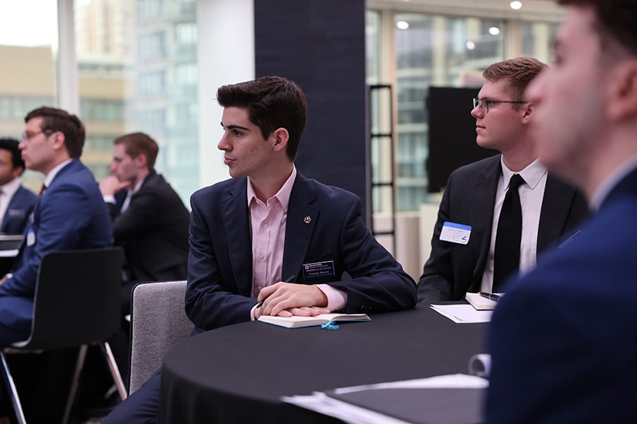 Business students in professional attire seated at tables for a professional development event.