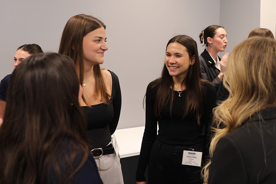 Students in professional attire talking together at a networking event.