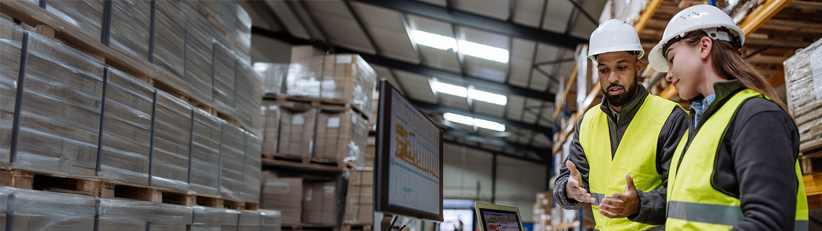 Warehouse manager talking with logistics employee in warehouse, planning transport of products, talking shipping process.
