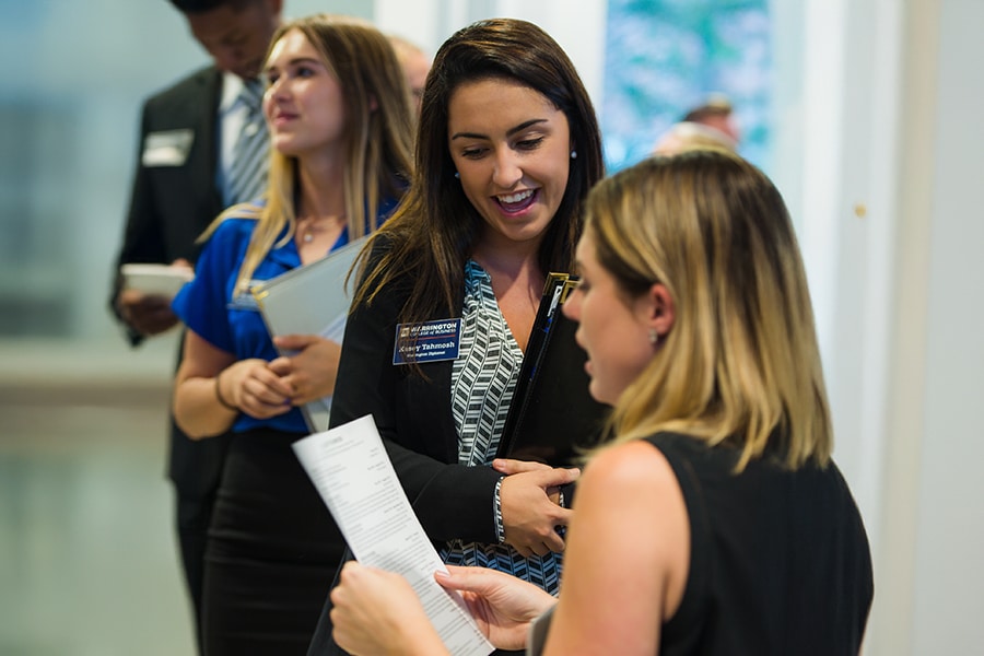 Warrington College of Business undergraduate students, in business dress, wait in line to have their resumes reviewed by Business Career Services