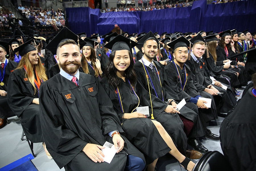 Warrington College of Business undergraduate students sit in a row in caps and gowns during the University of Florida's commencement ceremony