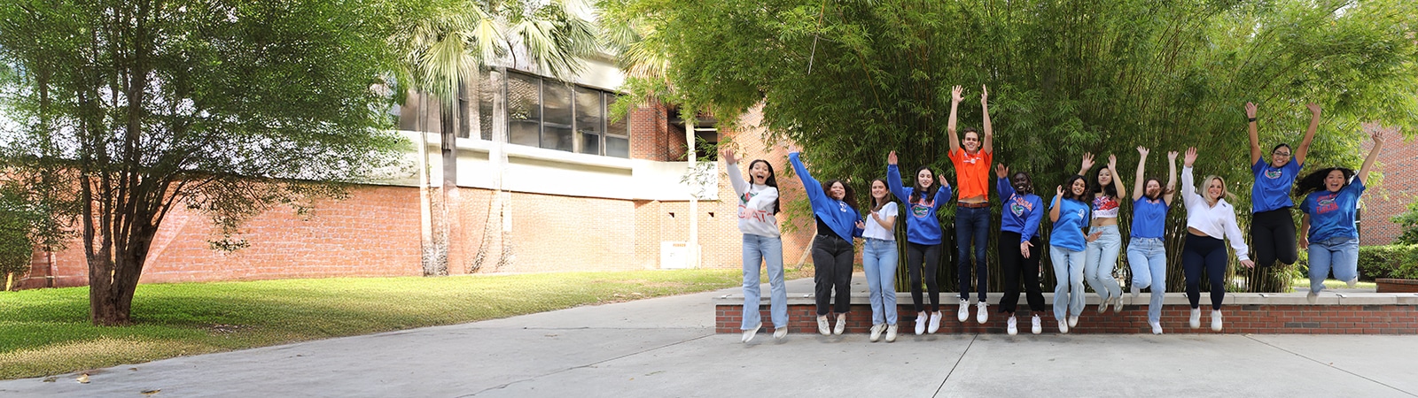 Undergraduates from the University of Florida Warrington College of Business wave their arms and jump up in the air outdoors