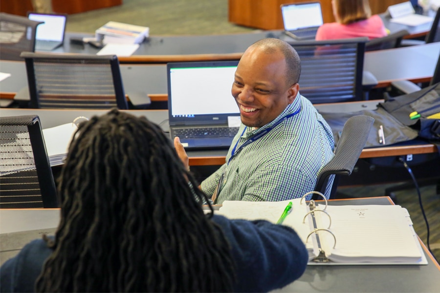 Two MBA students smiling and talking during weekend class session