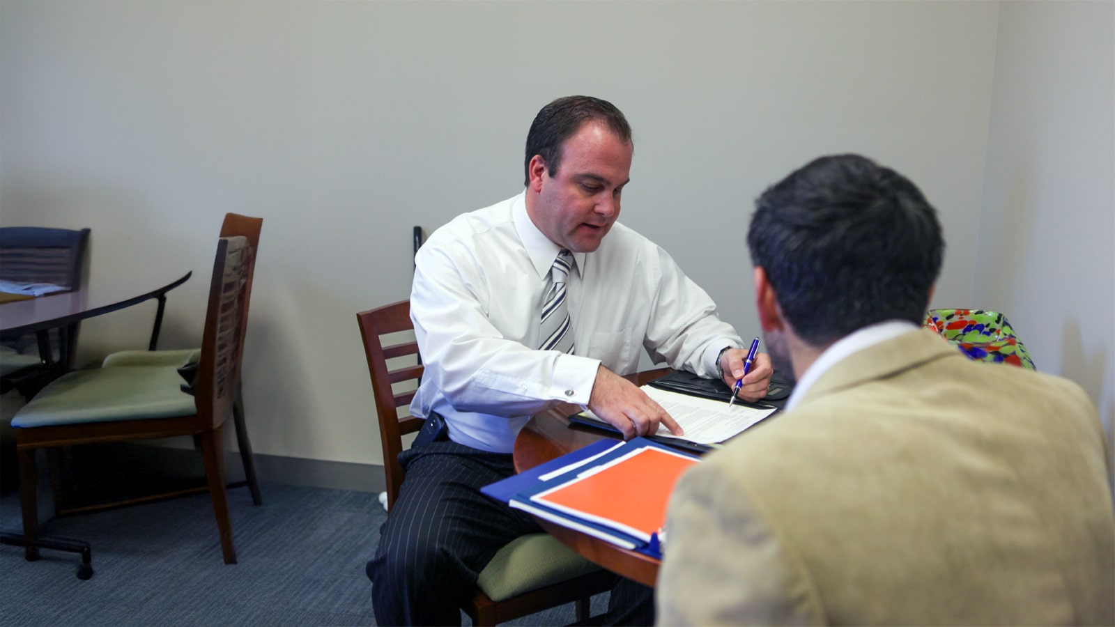 A career advisor and student sit across a table reviewing documents during a one-on-one meeting.