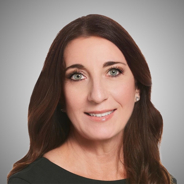 Professional headshot of Gina Avila, smiling, with long dark brown hair, wearing a black top and stud earrings, set against a gray gradient background.