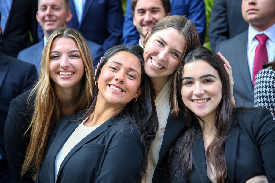 Group of smiling graduate business students dressed in professional attire