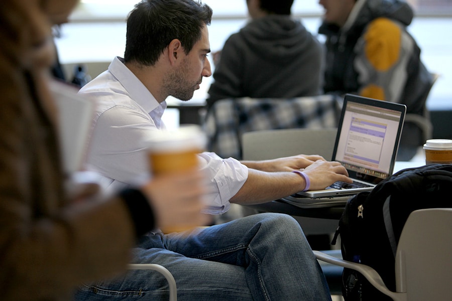 Graduate student sitting at a table working on his laptop.
