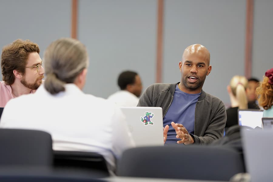 Graduate students sitting and working together at their laptops.