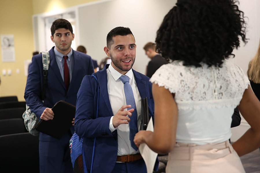 A line of graduate students waiting to speak to a recruiter. 