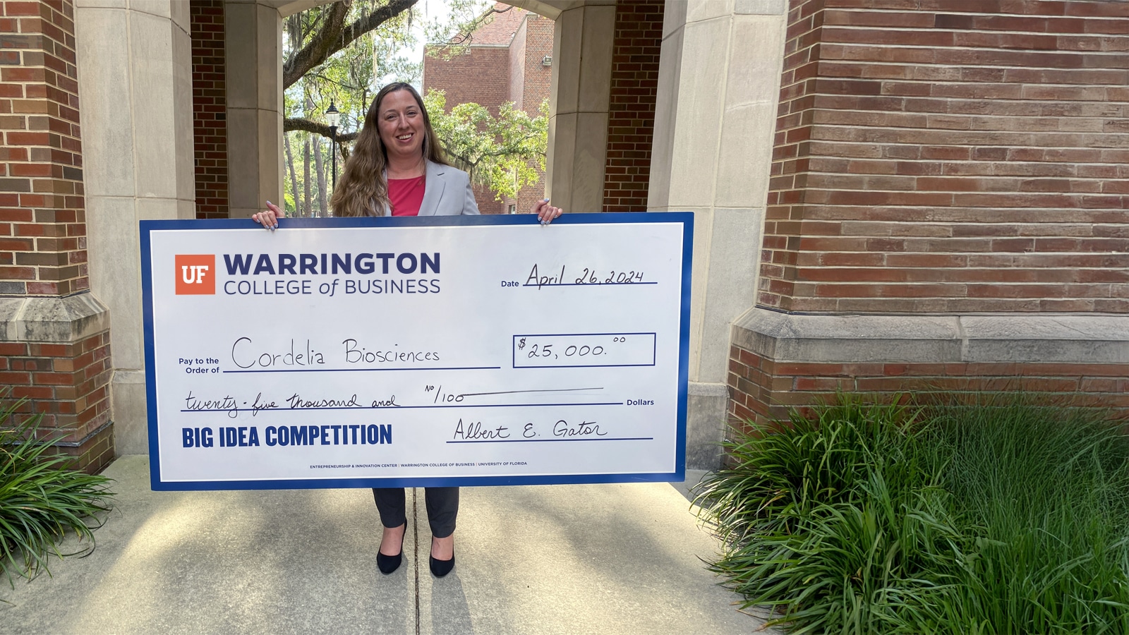 A student holding an oversized award check for $25,000.