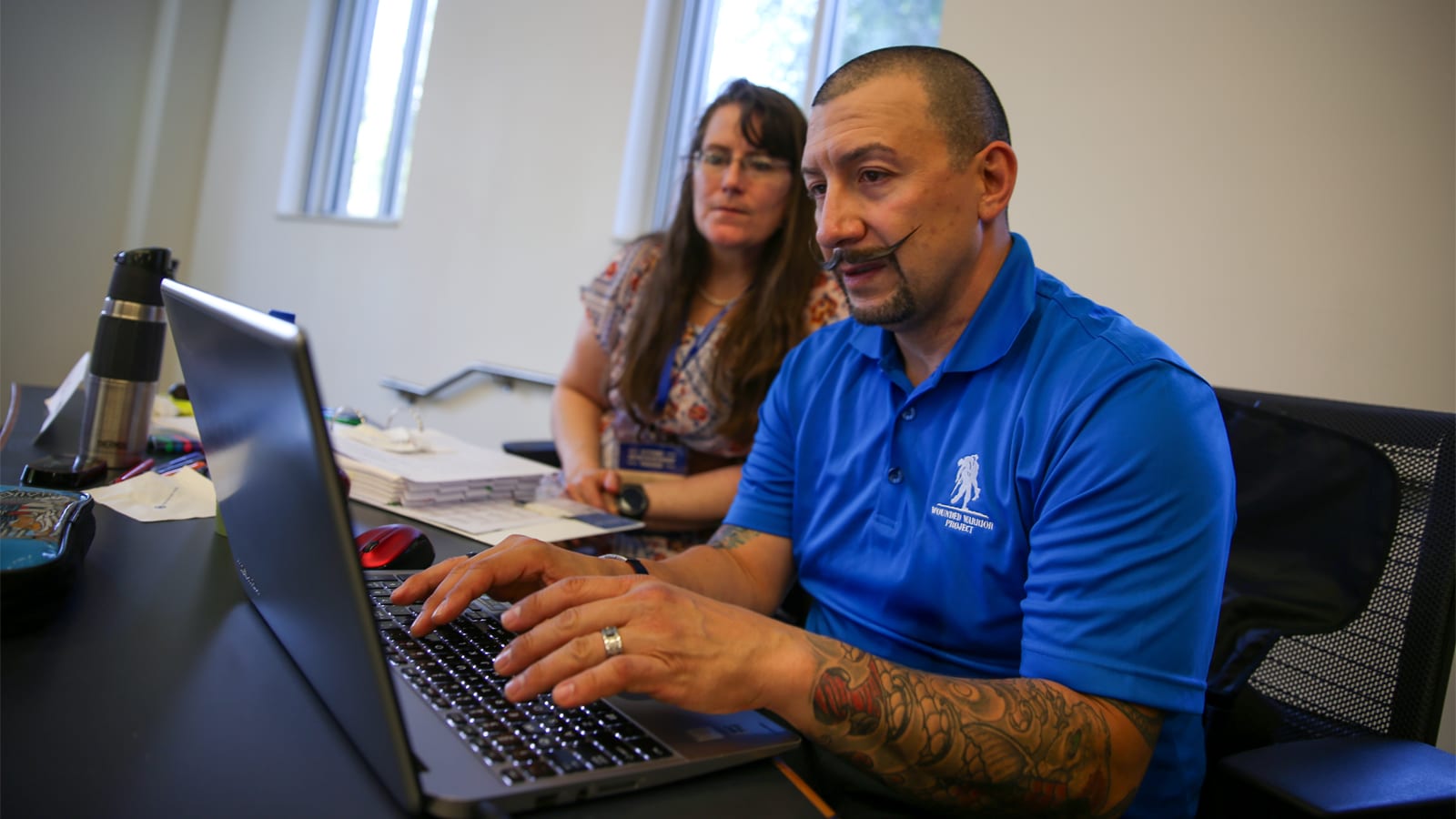Veteran in Wounded Warrior Project shirt works on laptop during MBA coursework
