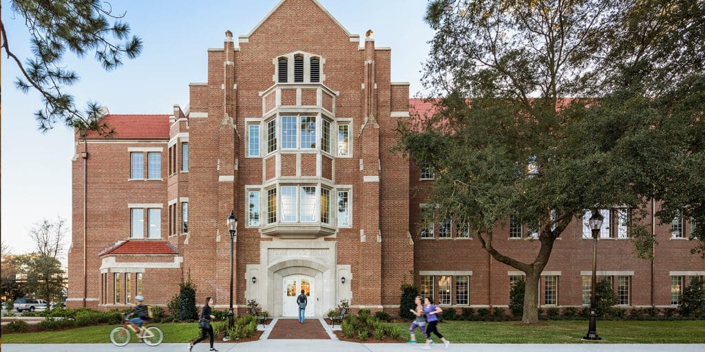 The north side of Heavener Hall as students jog, walk and bike by.