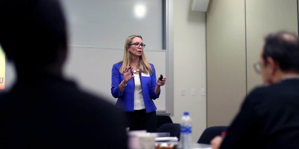 Women in professional attire speaking to PhD students.