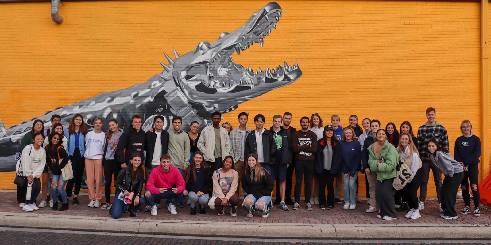 Group photo of Global Business Society members in front of a mural in downtown Gainesville.