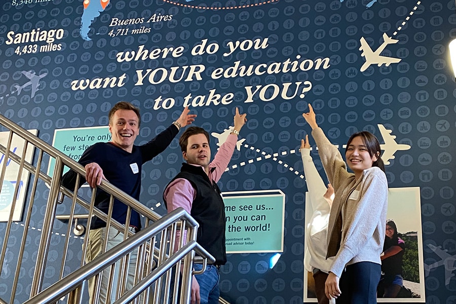 Global Business Society members pointing to a mural that says "where do you want YOUR education to take YOU?".