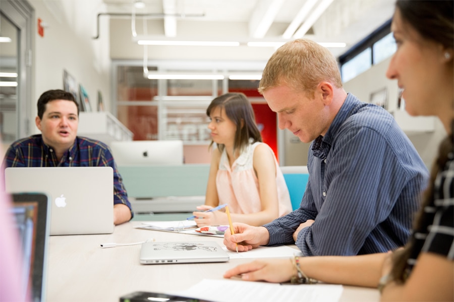 Four people with laptops sitting at a table in the Gold Lab.