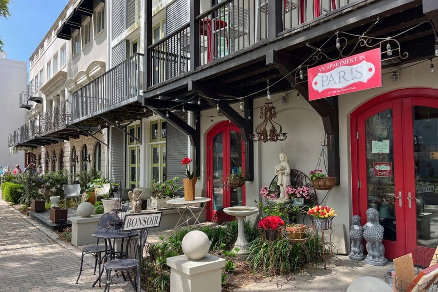 A brick walkway along shops with outdoor seating, landscaping and balconies