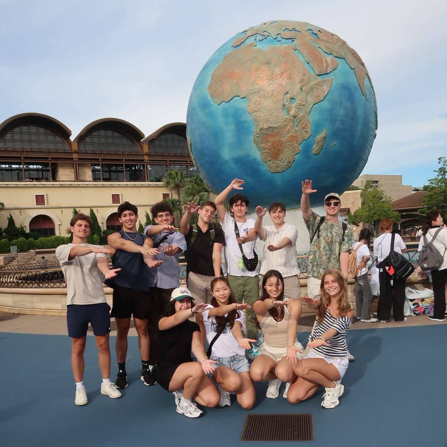stanley gatzek jr. with study abroad team doing the gator chomp in front of a globe