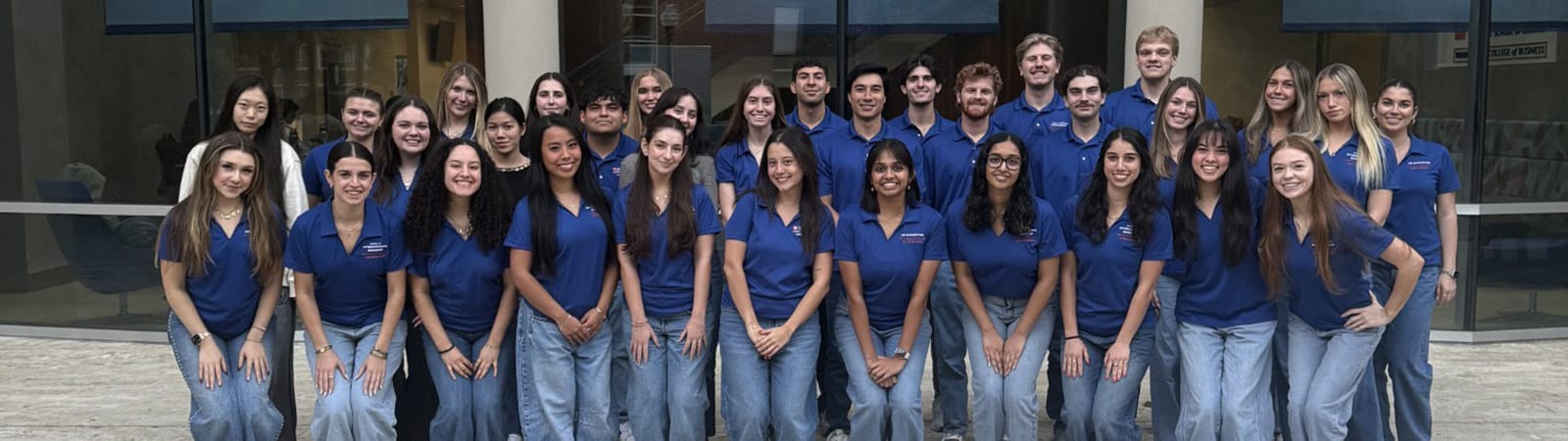 Graduate ambassadors, in their matching shirts, pose for a group photo with Hough Hall in the background