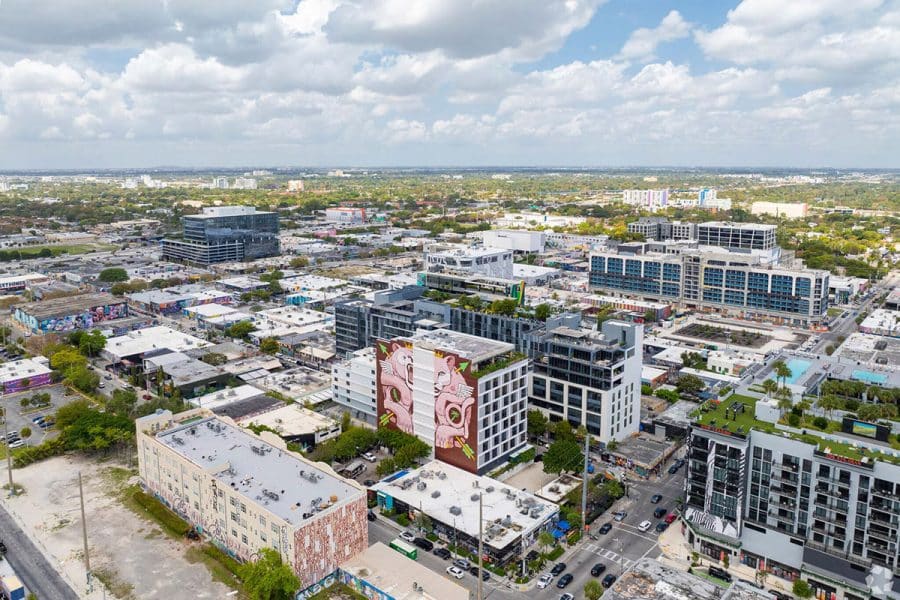 An aerial view of Miami's Wynwood neighborhood with a building in the middle that has a mural on one side and windows on another.