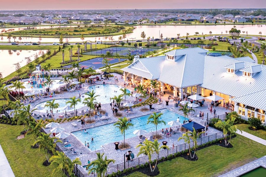 An aerial view rendering of the Lakewood Ranch development showing a clubhouse with pools, basketball and tennis courts, with lakes and houses surrounding it.