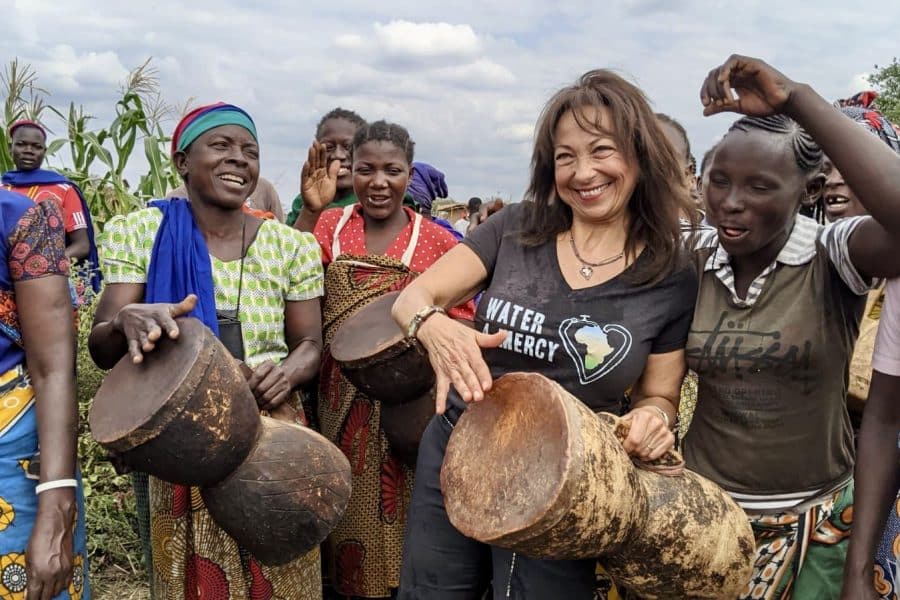 Nermine Khouzam-Rubin plays the drums, wearing a Water 4 Mercy shirt alongside women in one of the villages her nonprofit, Water 4 Mercy, worked in.
