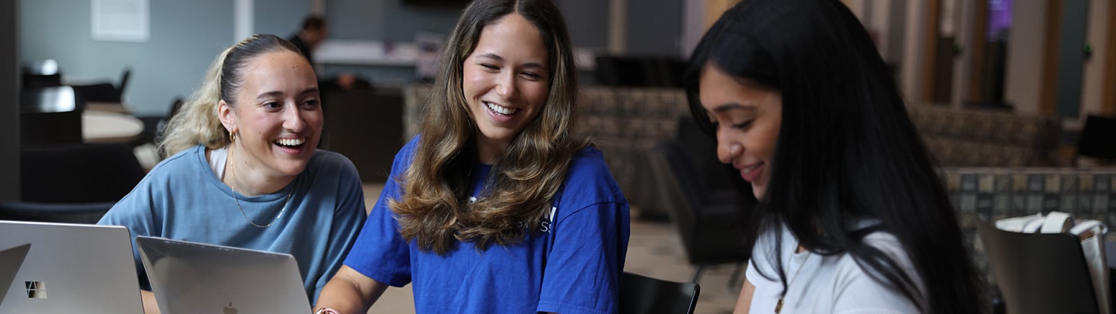 Young women sitting around a table laughing.