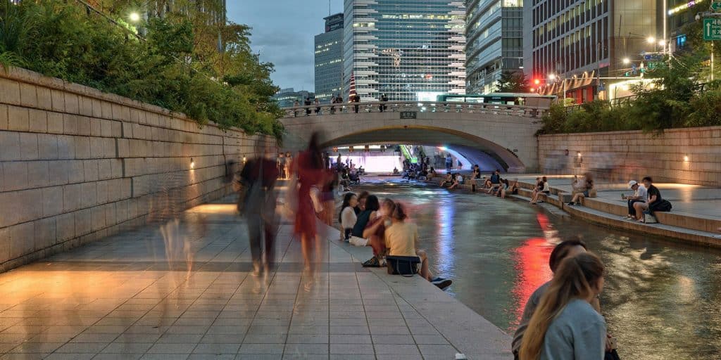 People walk and sit along the Cheonggyecheon River in Seoul, South Korea