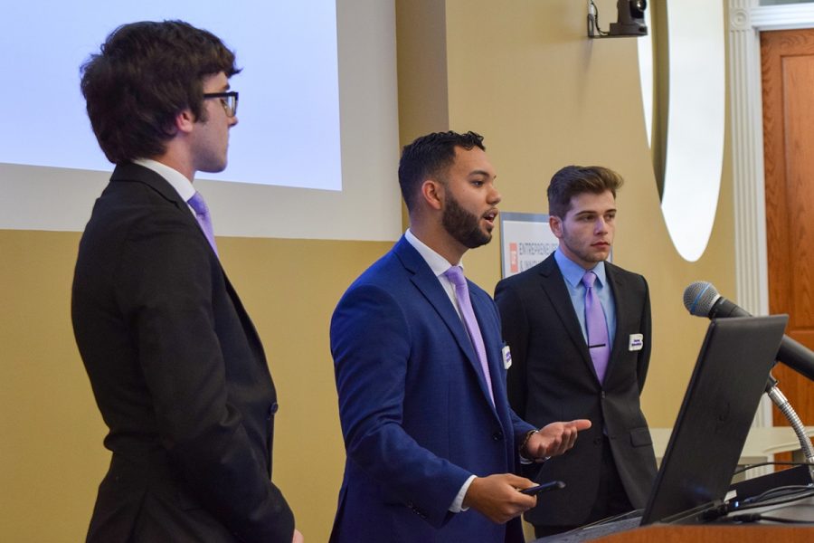 Three students speak at a podium.