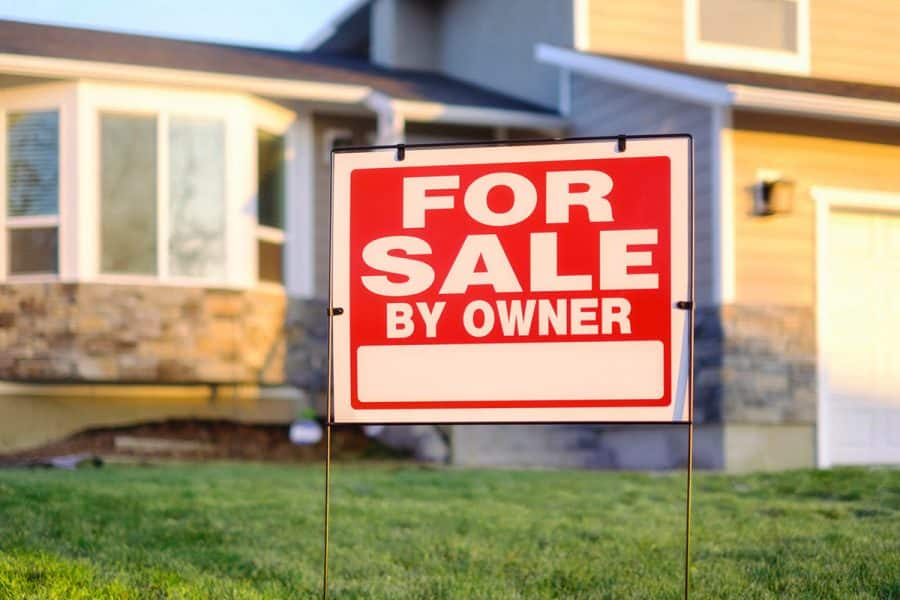 A for sale by owner sign in front of a residence