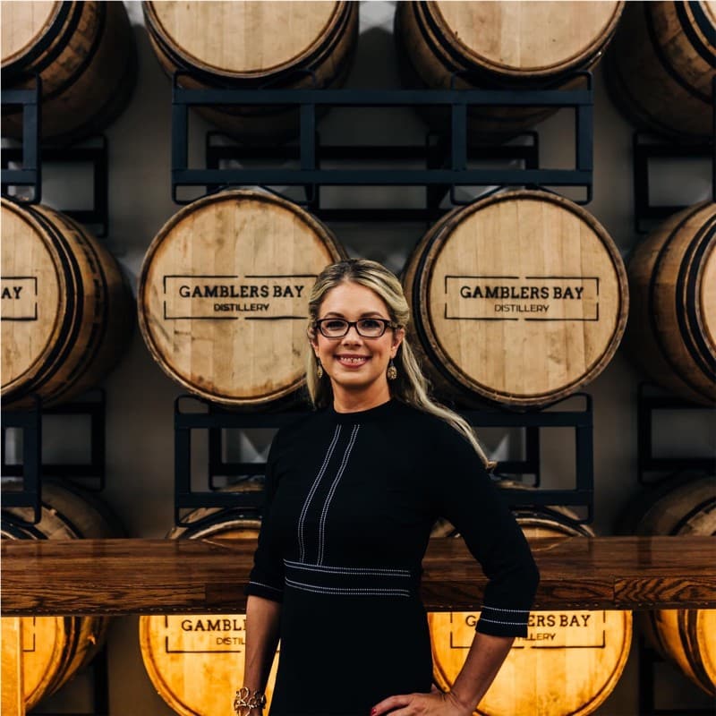Kerri Paun poses for a photo in front of a wall of whiskey barrels. 