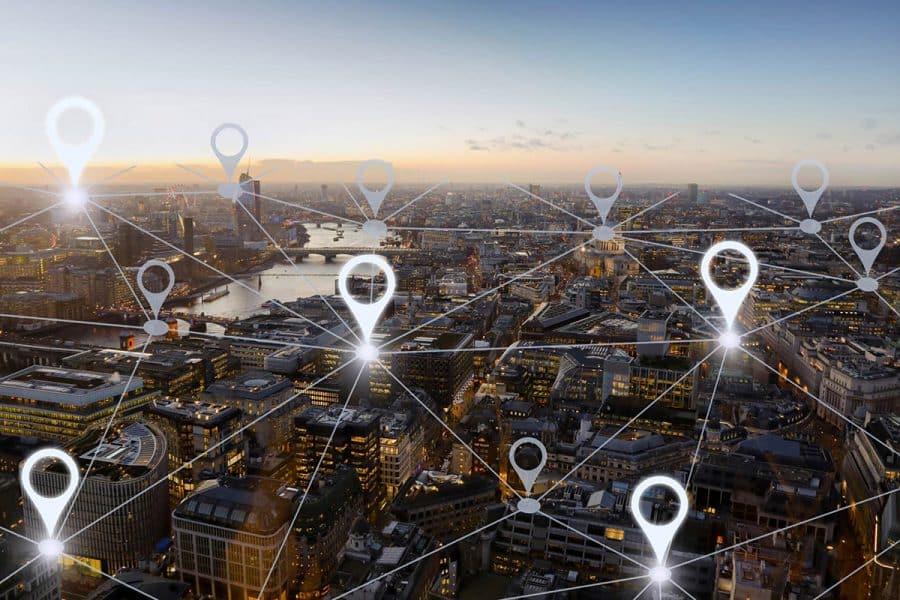 Aerial view of a large city sprawling to the horizon with location marker overlaid and lines connecting them