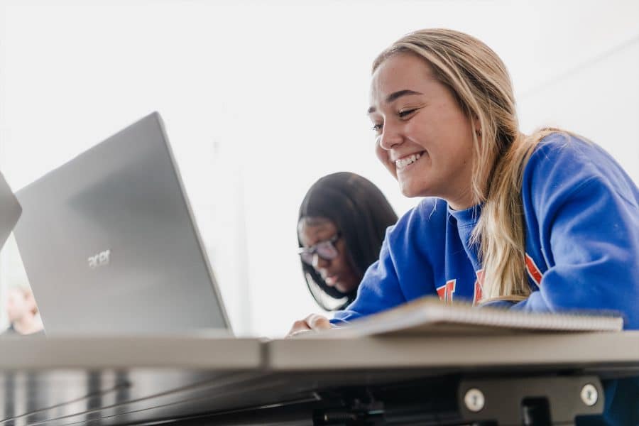 student smiling at her laptop in the classroom