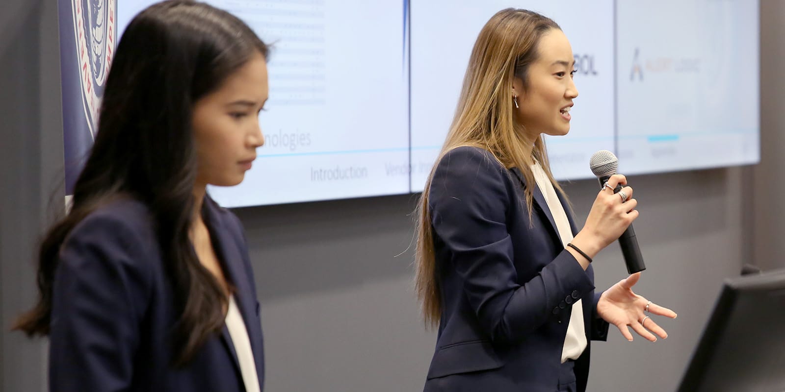 Two students presenting together in front of a screen.