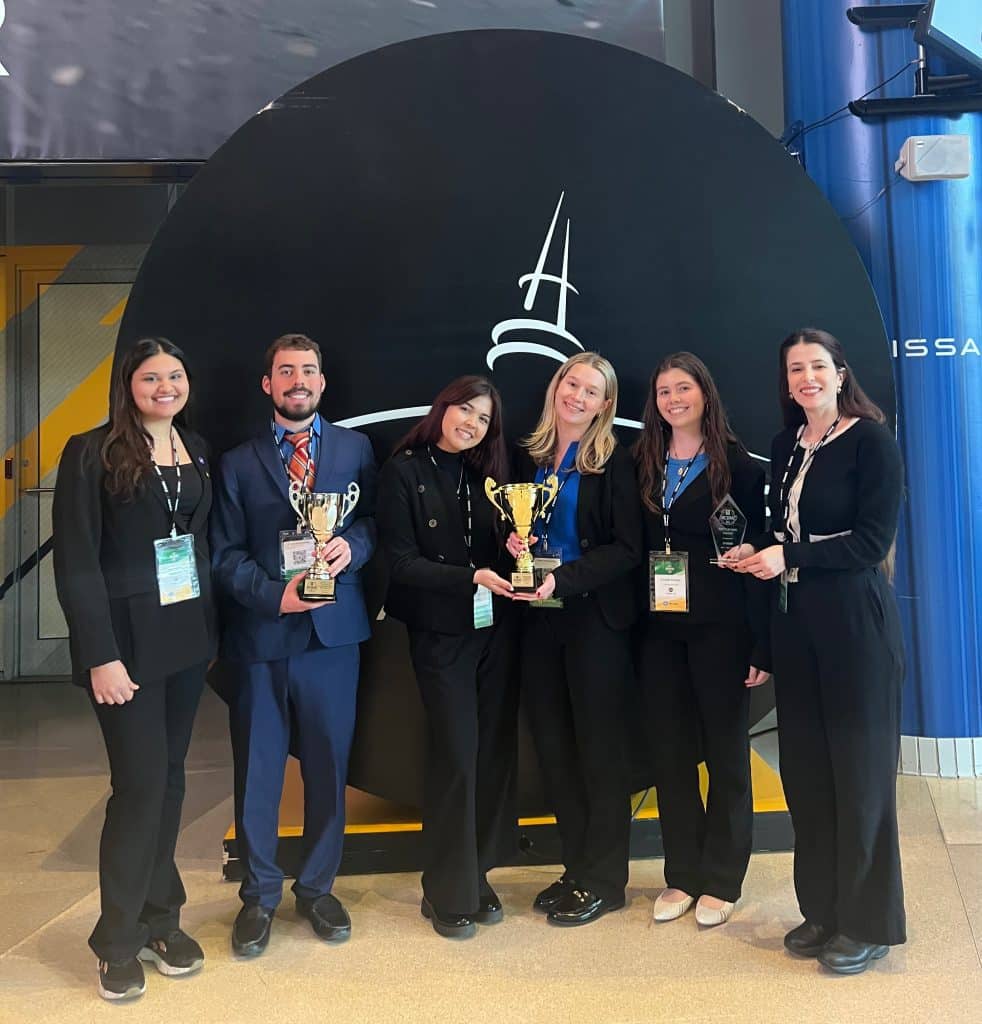 2026 National Collegiate Digital Marketing UF Team standing and smiling with Valeria Marcia with the three trophies
