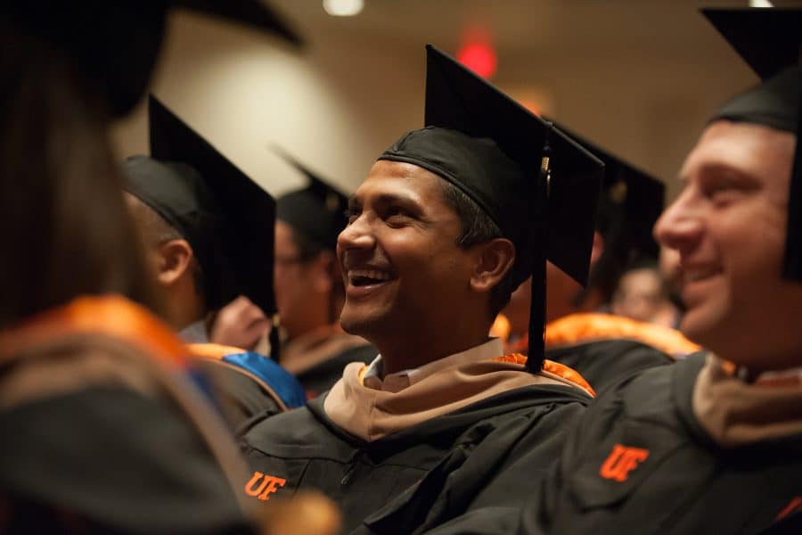 MBA student looking up and smiling with a cap and gown at graduation