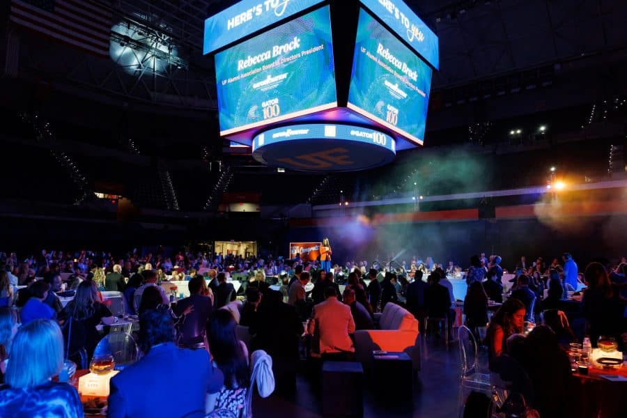 Rebecca Brock speaking onstage at the 2026 Gator100 award ceremony in the O'Connell Center