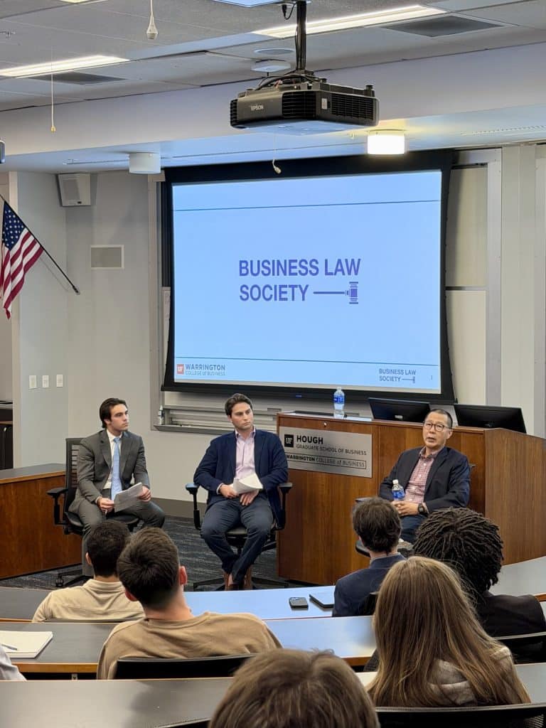 From left to right: Joaquin Heredia, Matthew Smith and Robert Rhee sit at the front of a classroom delivering a talk at a Business Law Society meeting.