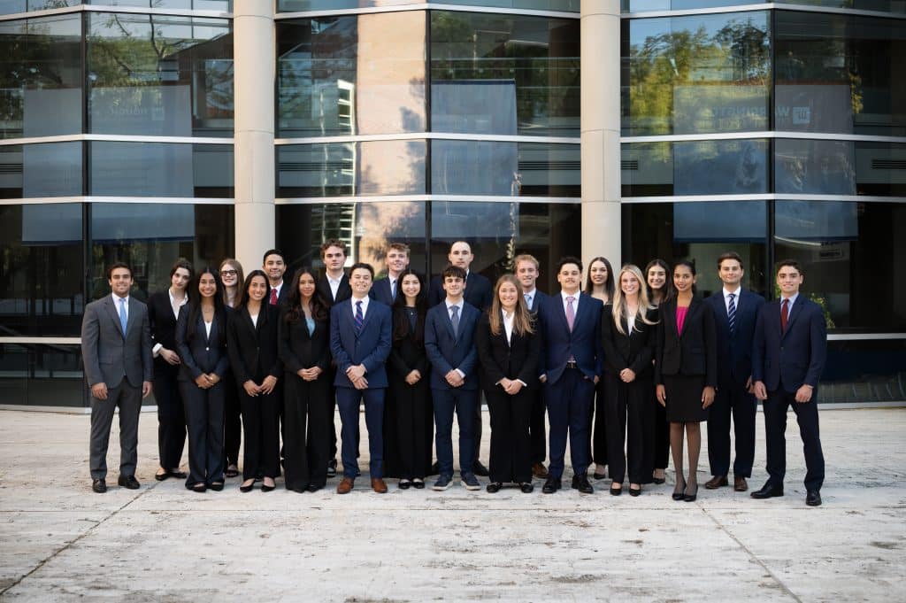 The members of Business Law Society pose in front of the glass windows at Hough Hall.