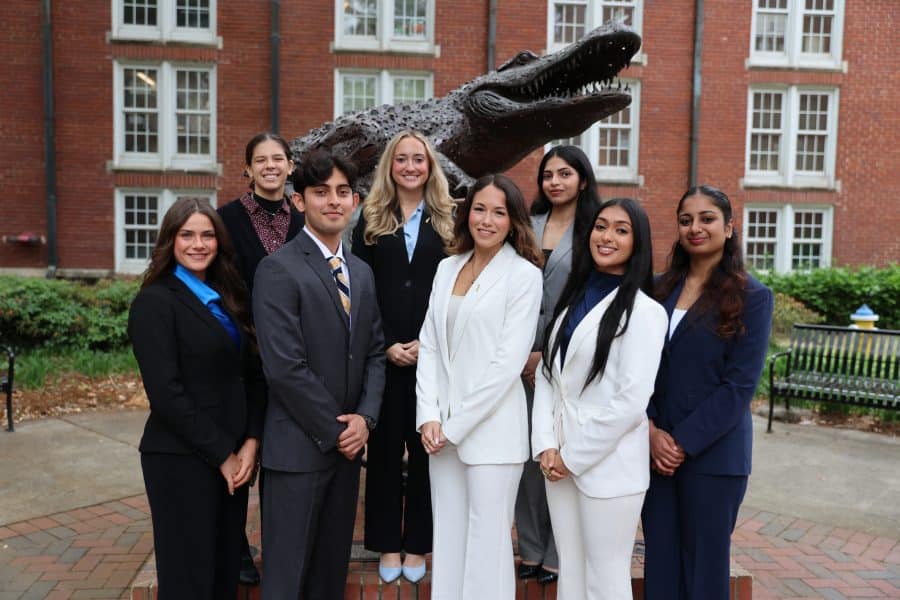 Heavener Hall of Fame and the Distinction in Leadership & Service Award student winners standing in front of the Heavener Gator Globe statue with their hands crossed and smiling