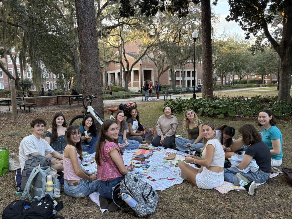 UF Eco-Gator members sit on picnic blankets in Plaza of the Americas while making bookmarks out of repurposed fabric.