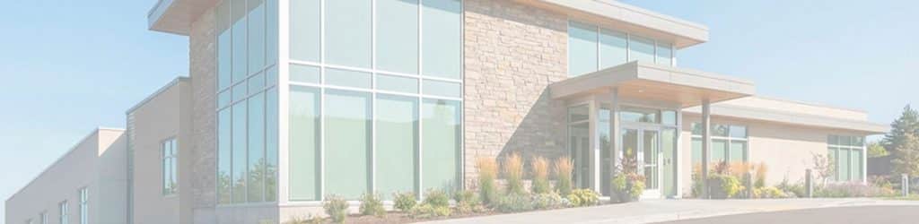 A building front with big windows, stone facade and nice landscaping.
