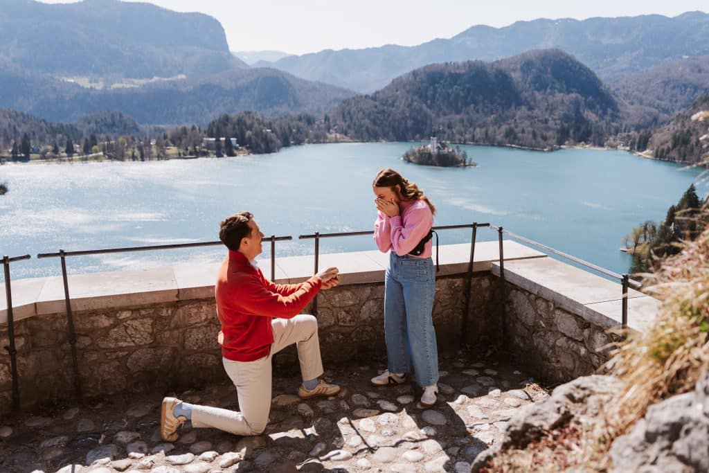Michael Morin proposes to his wife in front of a body of water with mountains in the background.