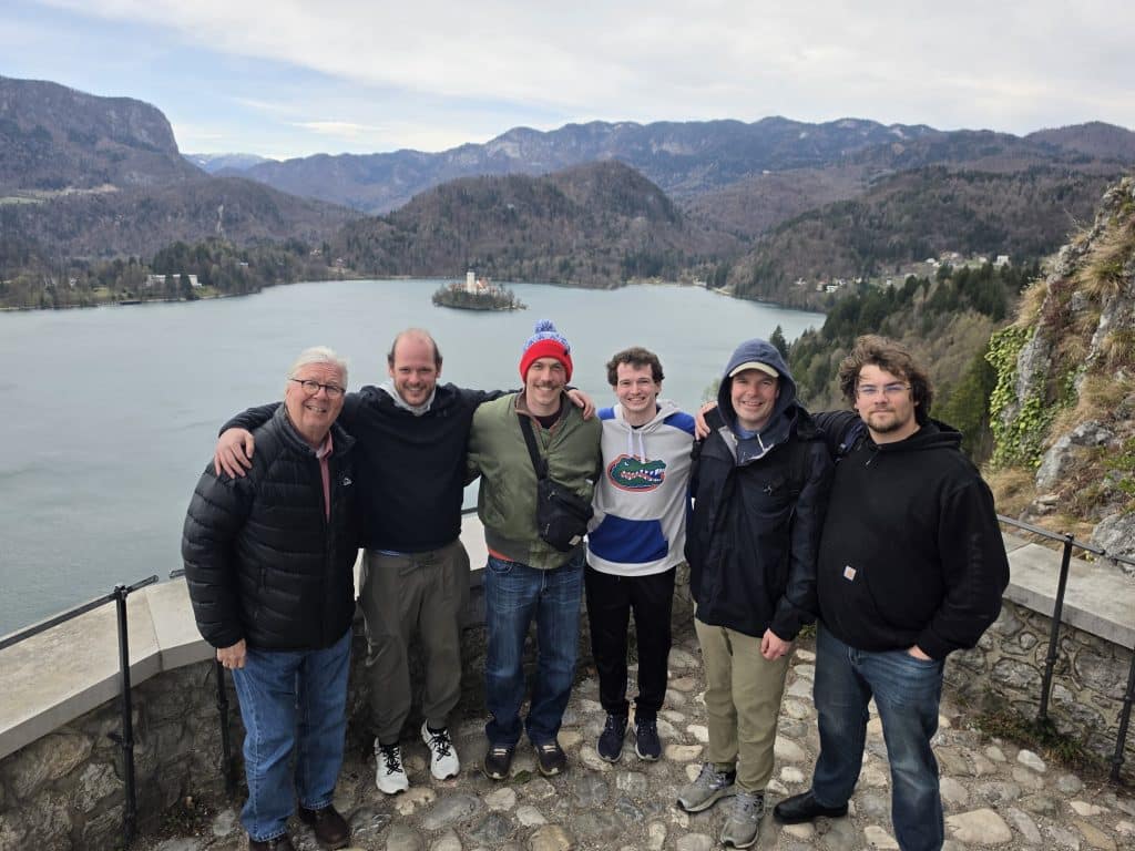 MBA students pose with Gary A. McGill in front of a body of water with mountains in the background