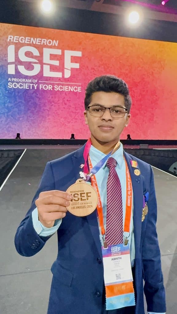 abhith kasala holding medal in front of a ISEF screen