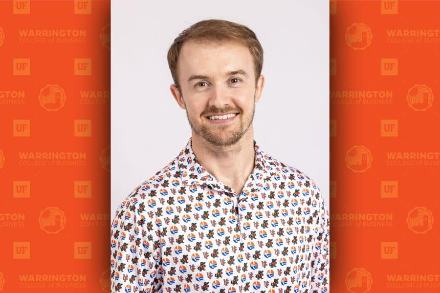 A vertical photo of Sean Warner centered in front of a horizontal orange background.