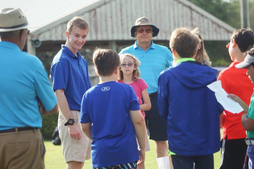 Gator Junior Golf Association volunteers work with children during a golf activity.